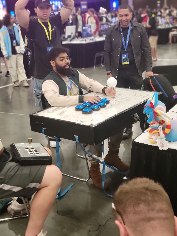 Bentlee at Evo playing Street Fighter on an arcade stick that is about five feet across with a stick the size of a club and buttons like on Family Feud 