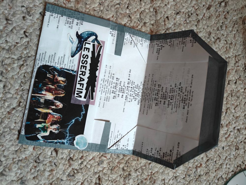 White paper folded to hold a CD. In small typewriter type font, the lyrics to various songs from the Easy, Crazy, Hot albums are written. The CD case is opened to show the inside and how the CD easly slides in. 