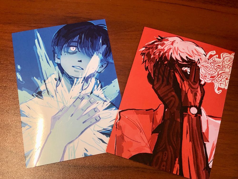 two art prints featuring the main characters of "the summer hikaru died." the blue art print of yoshiki features him holding out a hand over his bright shining star-like soul. the red print of hikaru has him peeking out through one hand at his own horror with blood running down his arm as his true form starts to leak out of his pupil.