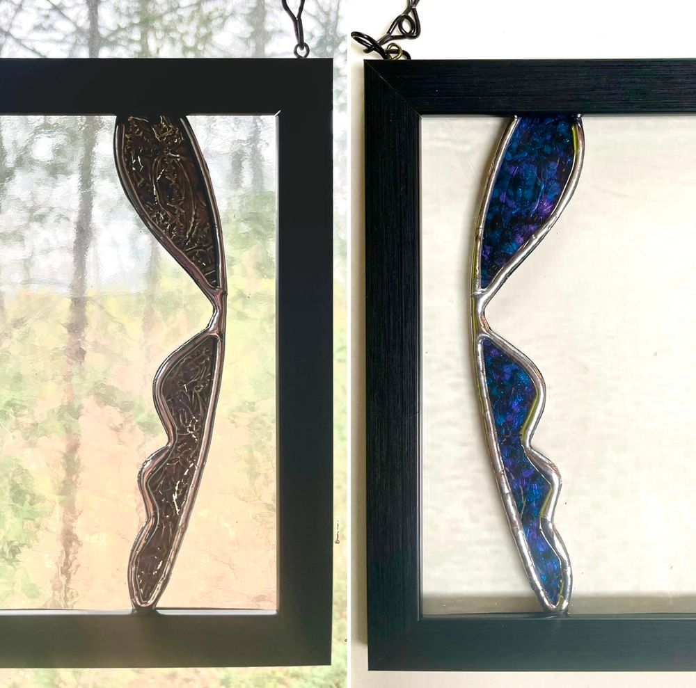 Two stained glass silhouettes, comprised of small inserts of blue and gray color to create the impression of faces in the void.