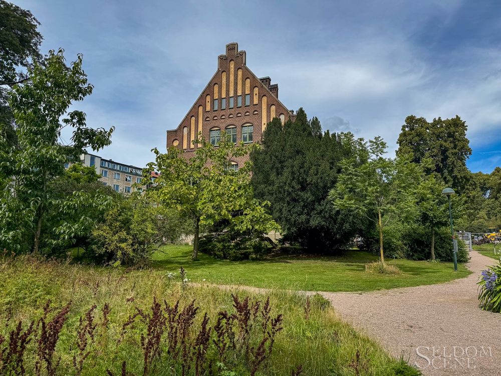 A historic museum emerges from vegetation in botanical gardens.