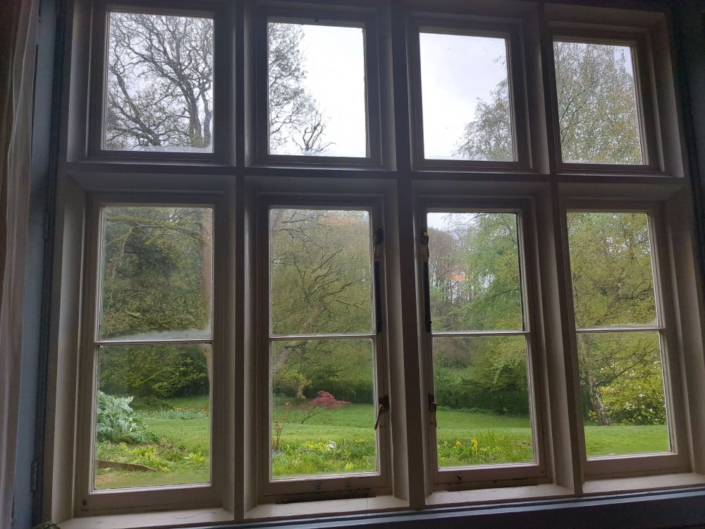 View from a Stone Window into a lush green garden with trees and hillside beyond
