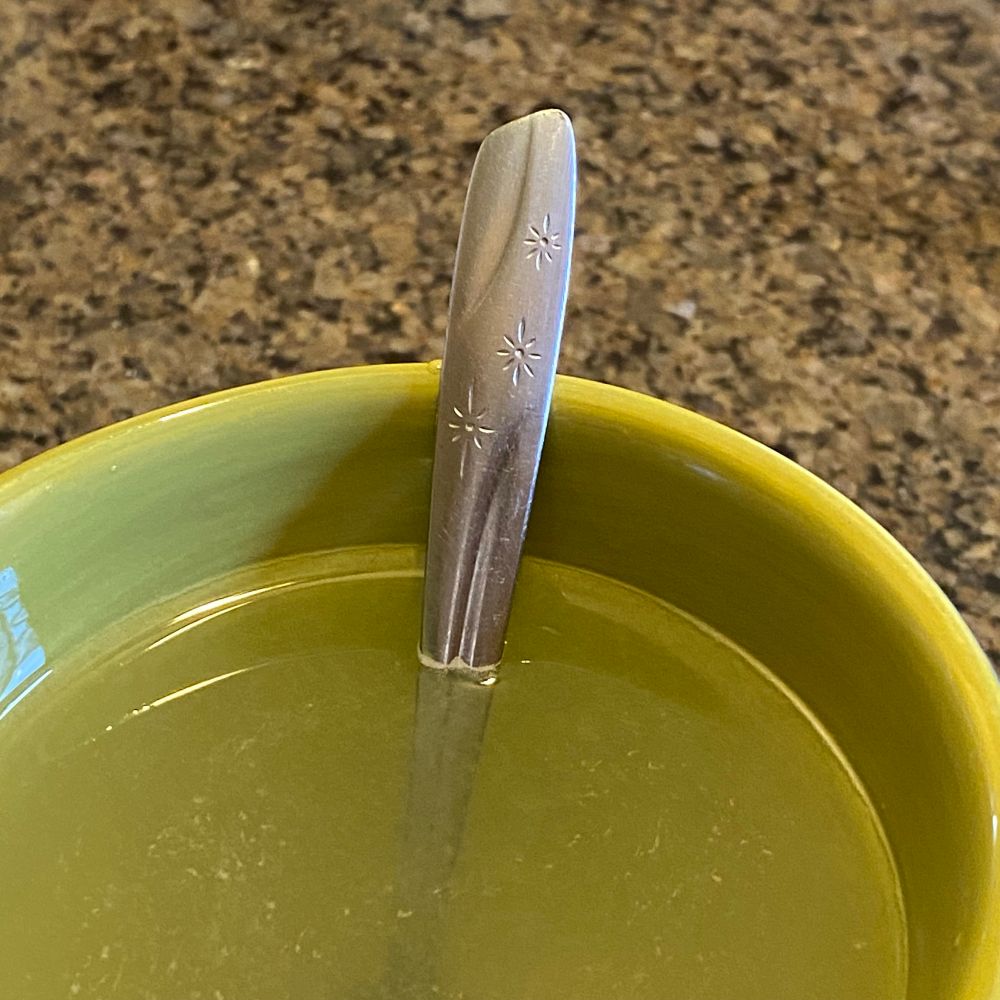 Stary spoon i side a green mug with lemonade 