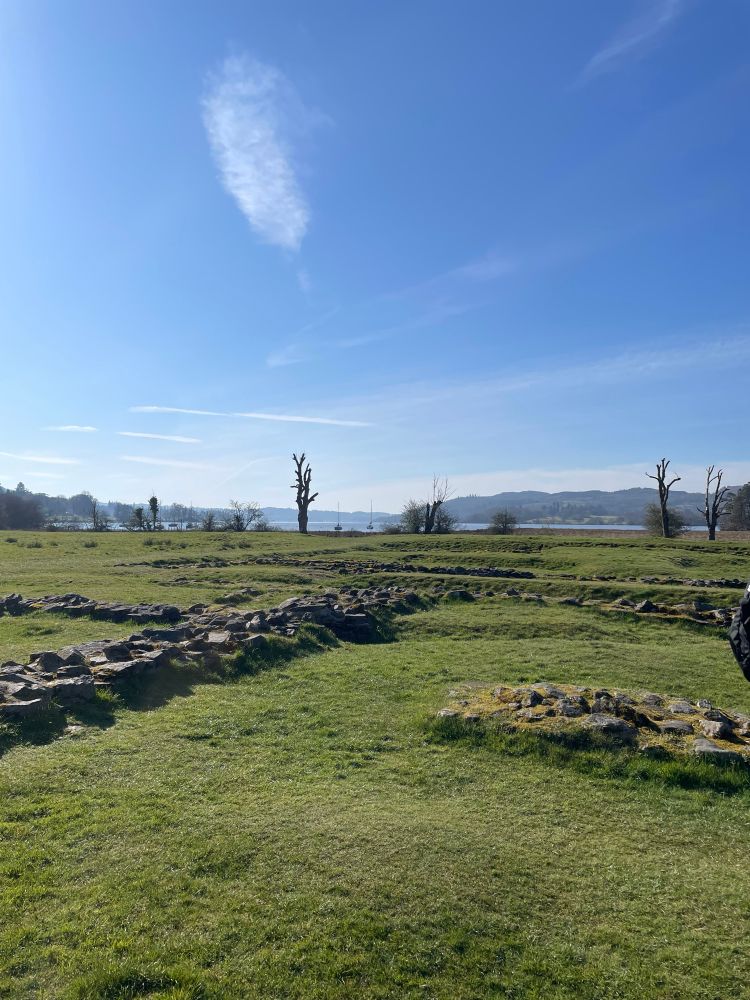 Ambleside Roman Fort under a bright blue sky with Lake Windermere visible in the background 