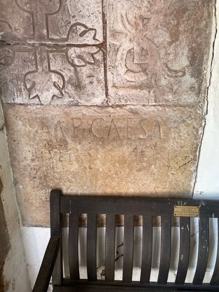 Photo of RIB 757 in the wall of the entranceway of the church at Brough, with a bench in front of it . IMP CAESA[R] very clearly visible in the first line. 