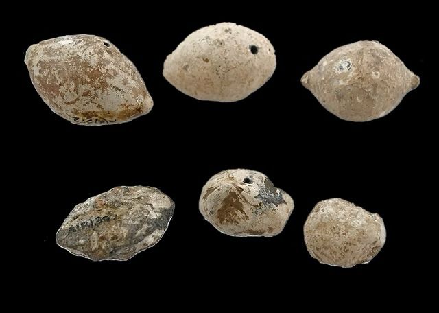 Professional photograph of lead sling bullets from Roman Ambleside, taken by Durham archaeology students Rowan Colley and Isla Mustin. The bullets are cream coloured. Some are lemon-shaped, and others are more hastily formed blobs. 