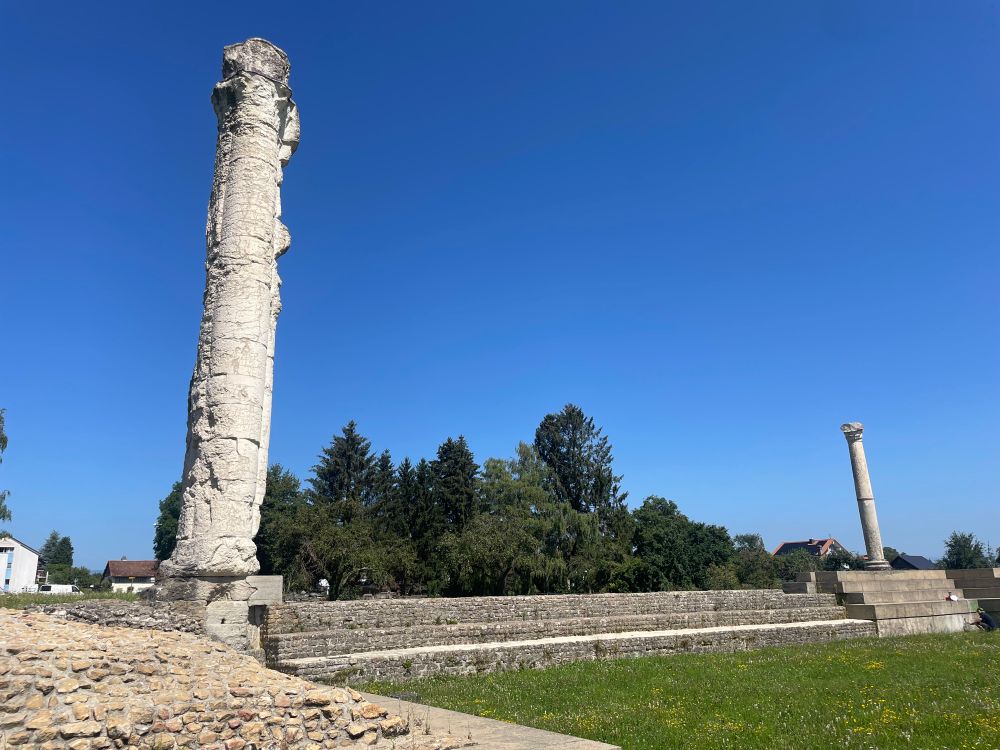 View of the white limestone column of the Sanctuaire du Cigognier at Avenches on a sunny cloudless day (with another reconstructed column in the distance).