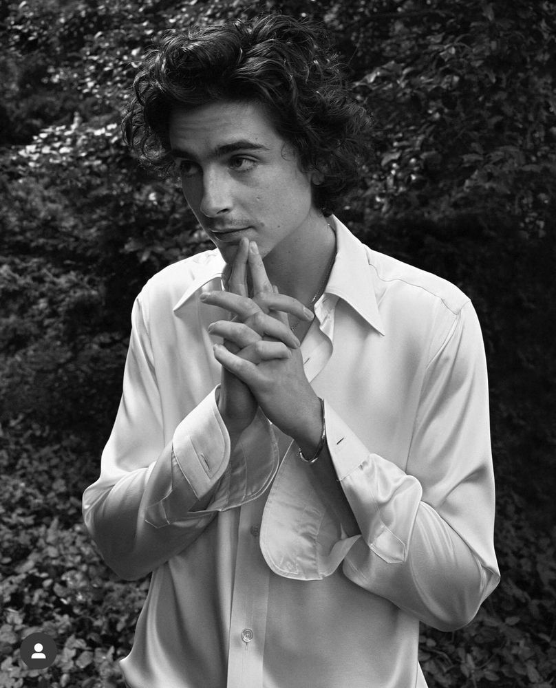 Timothée Chalamet in white shirt and trousers. Black and white photo