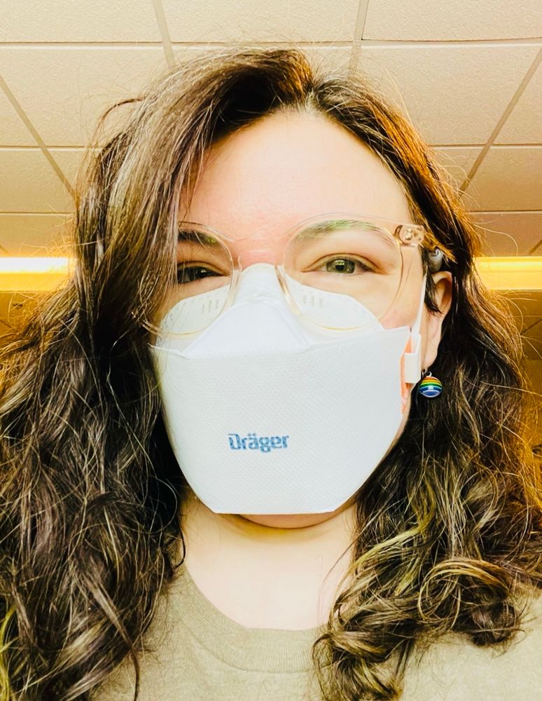 I'm wearing a drager N95 mask  and an olive green shirt. My long wavy brown hair is down over my shoulders.