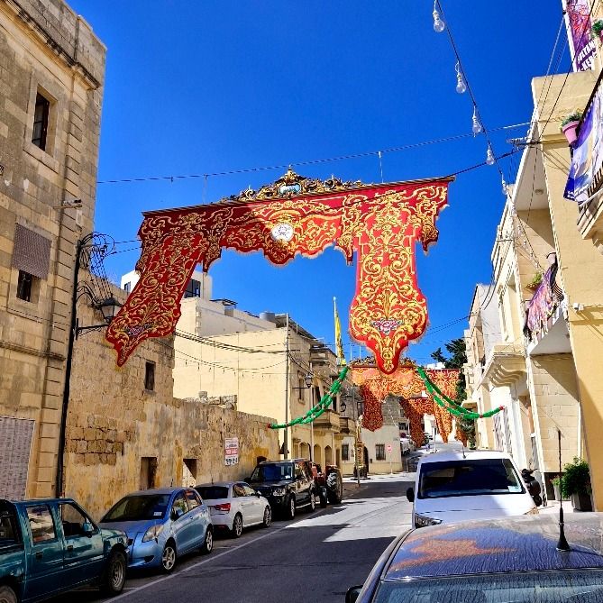 Highly decorative bandalori, ornate red and gold banners, hang across a village street.