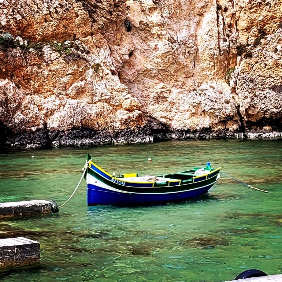 A traditional Maltese fishing boat, a Luzzo, moored by a dock on the Inland Sea.