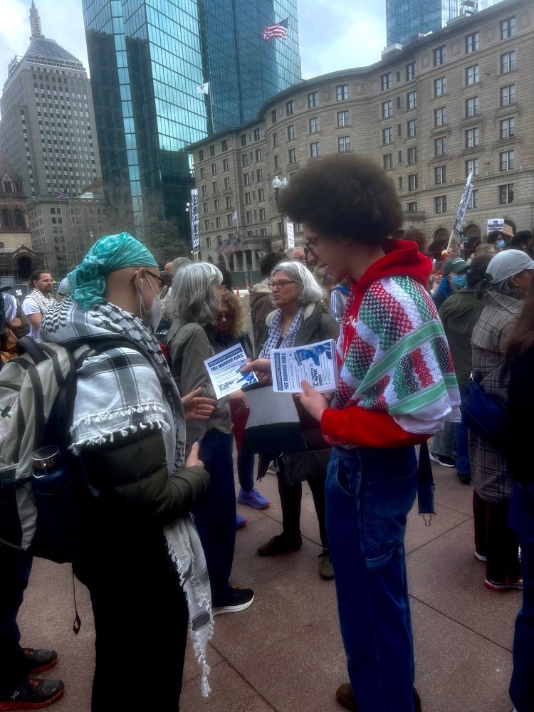 Demonstration for Mahmoud Khalil in Boston on March 16, 2025. Two people wearing keffiyehs exchange literature.