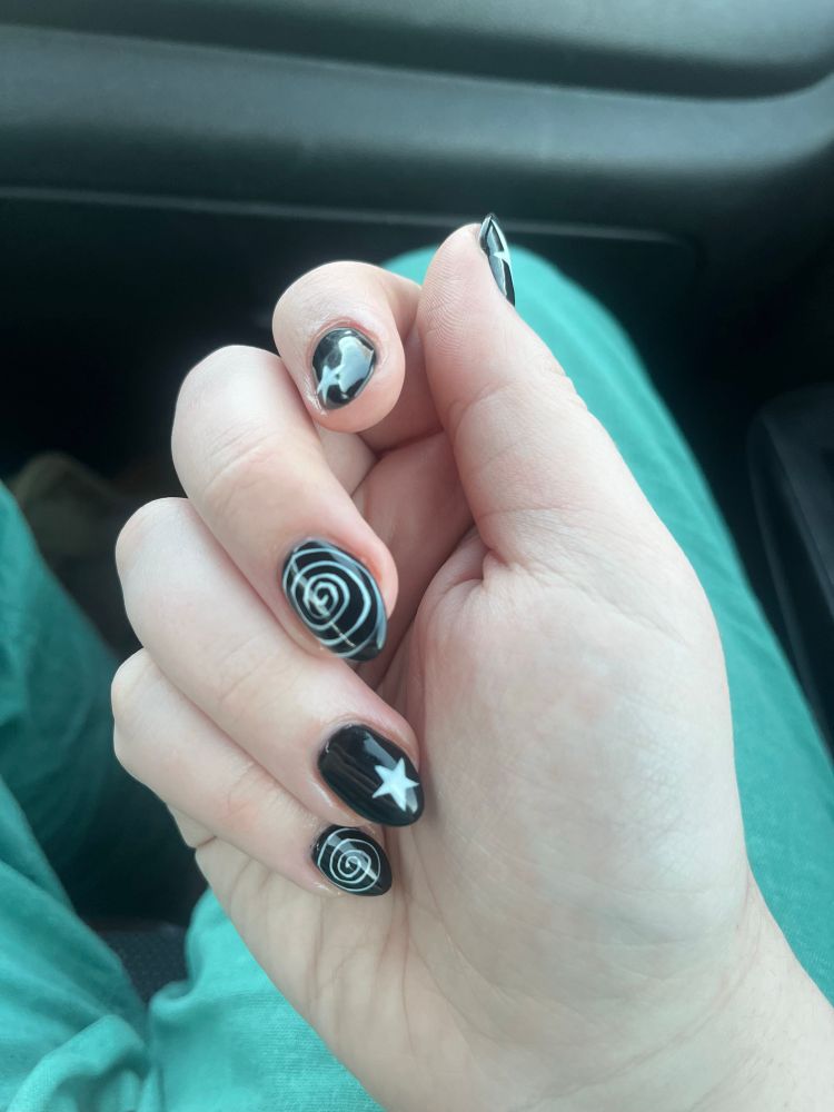 skylers freshly done fingernails, slightly pointed, black, with white stars and spirals on alternating fingers.