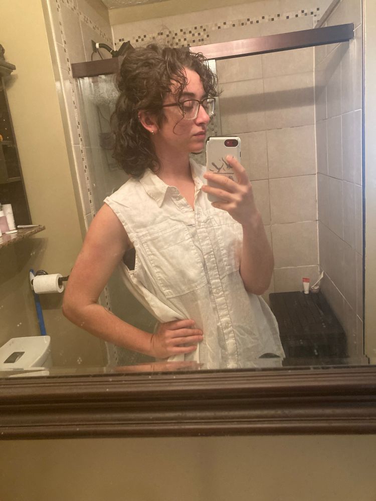 photo of the author, a person with dark brown hair and visible greys that are, for the first time in their life, arranged in effortlessly defined curls 