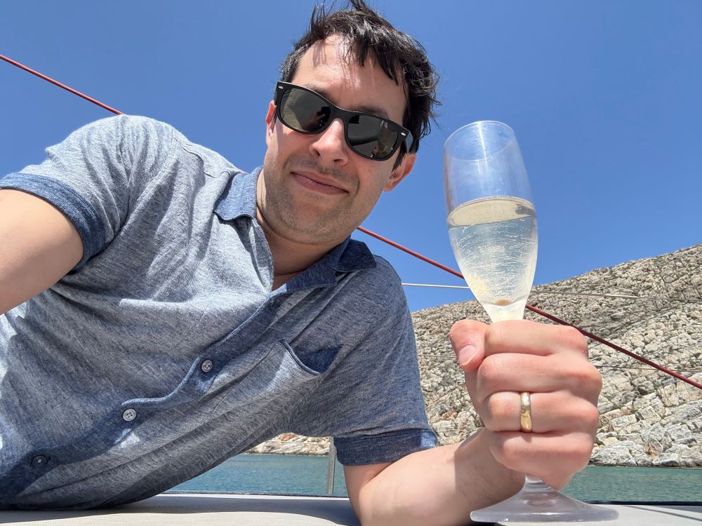 Ben with a glass of wine on a boat in a very old-man looking shirt