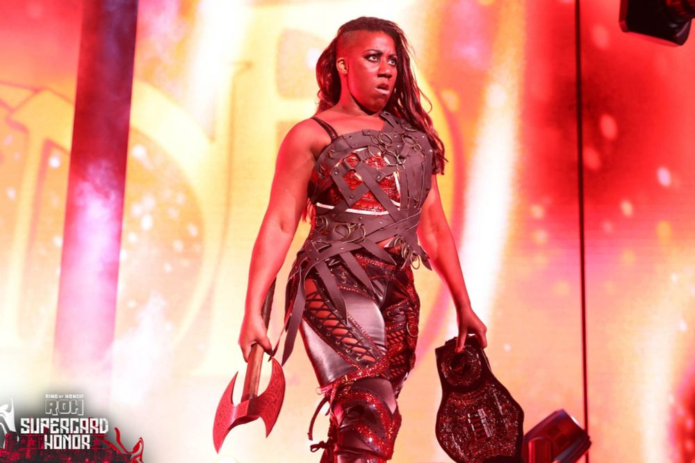 A shot of Athena Palmer, a wrestling heel, walking to the ring in Karlach cosplay while holding the RoH championship belt.