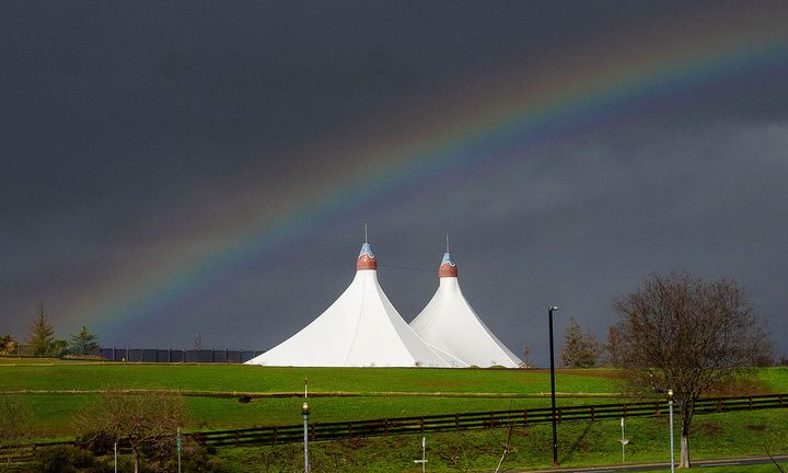 A rainbow fills the sky over the twin white tents of the Shoreline Amphitheatre during a break in Thursday's storm.