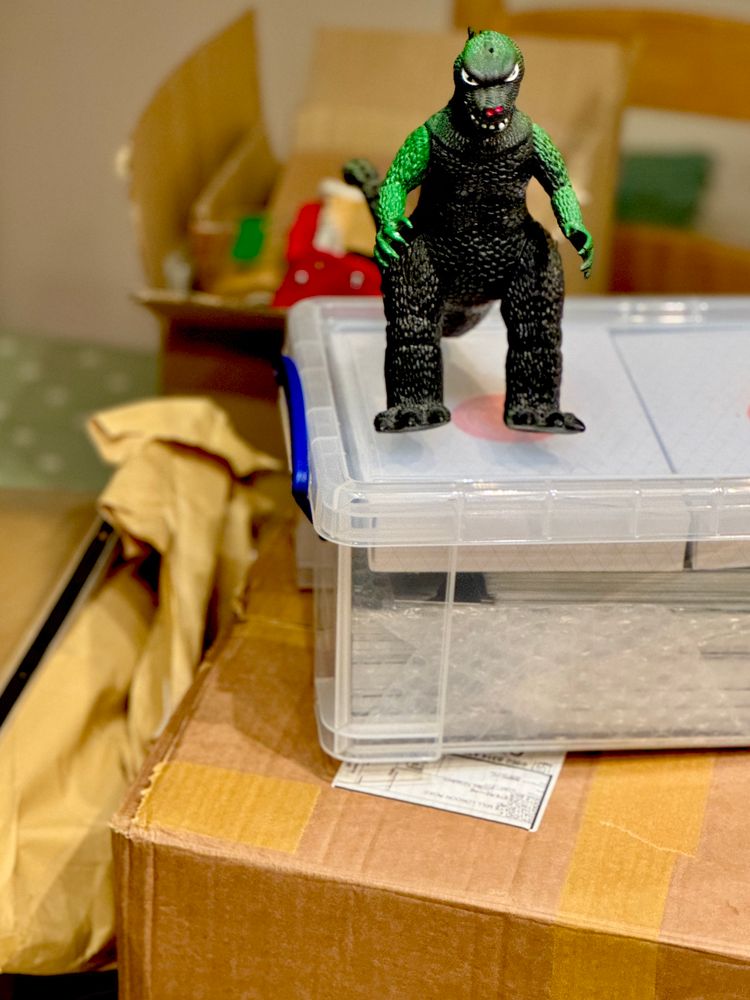 A toy Godzilla sits atop of a mountain of amazing artwork that will be on its way to Thought Bubble Festival 2025