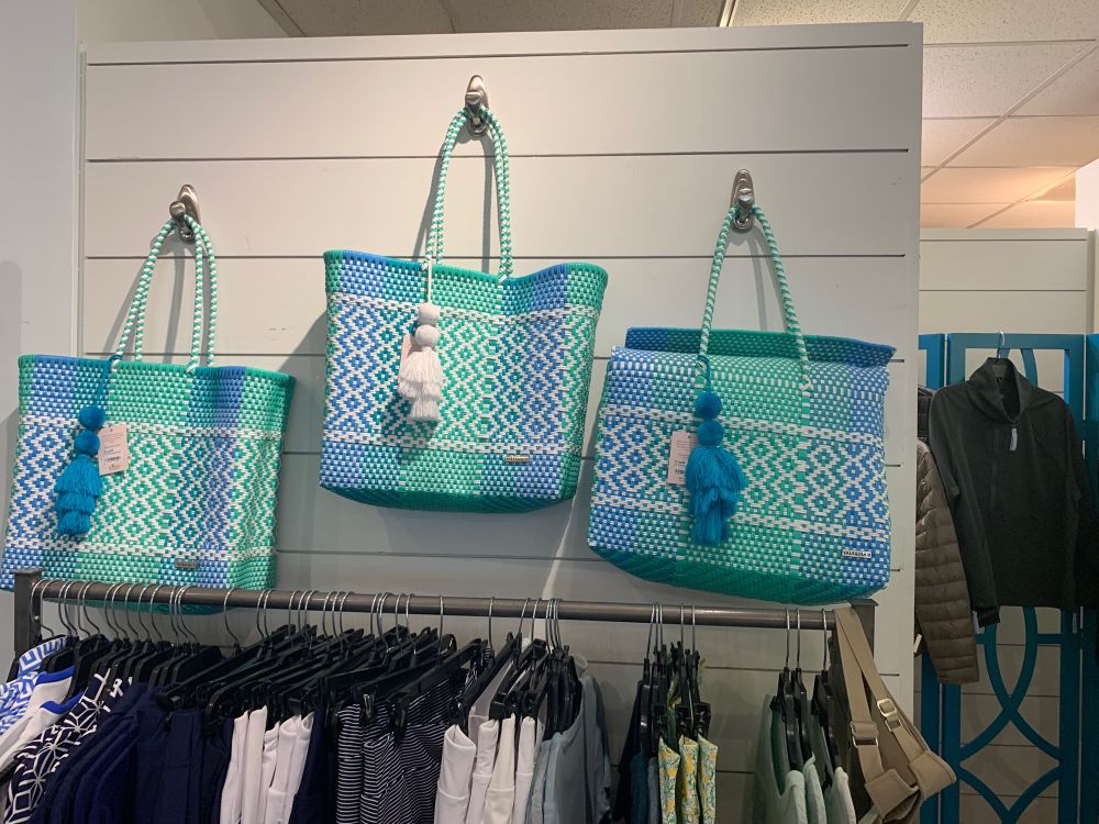 Three blue and green bags with a tassel on the zipper hanging on a wall 