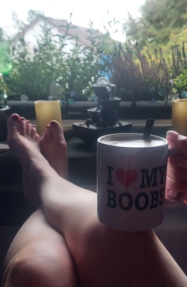 Zwei Beine auf der Fensterbank .
In der Hand eine Kaffeetasse .