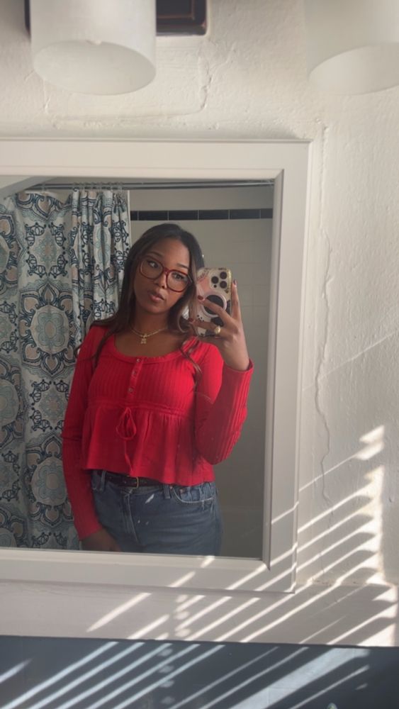 Woman in red shirt taking a mirror selfie in a bathroom medicine cabinet mirror
