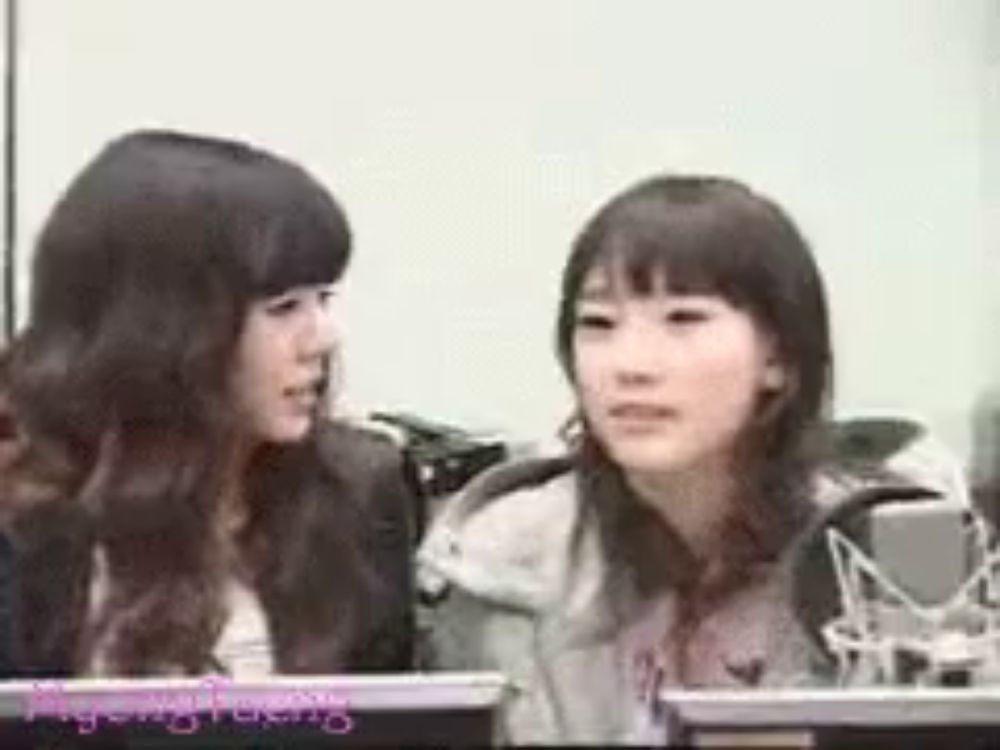 two girls are sitting next to each other in front of a microphone and looking at each other .