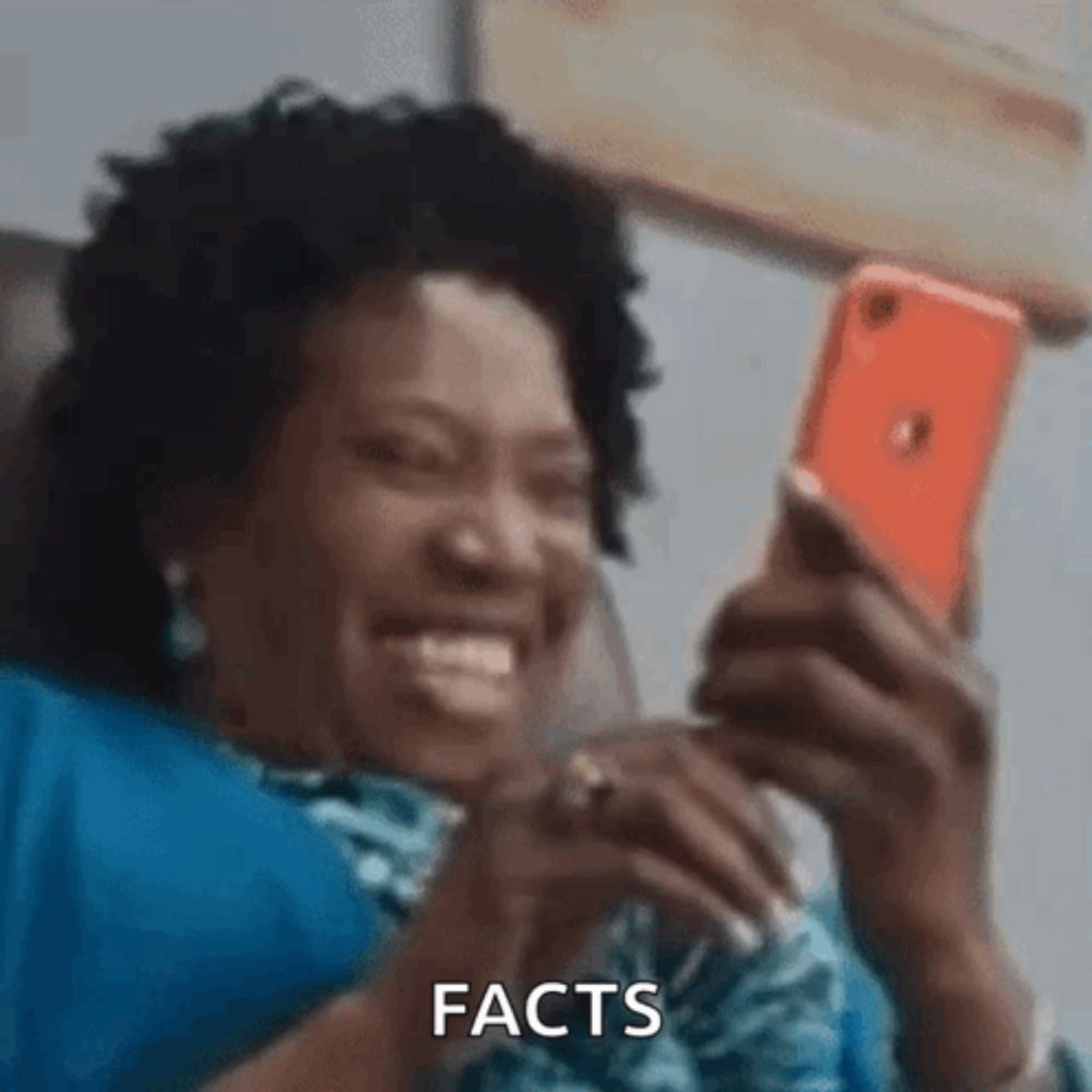 a woman is laughing while looking at her cell phone and saying facts .