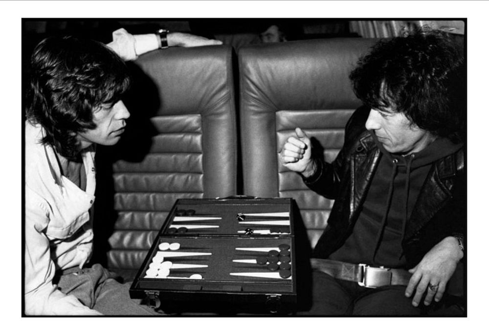 Photo by Michael Halsband of Mick Jagger and Bill Wyman playing backgammon on their tour jet (1981)