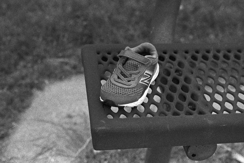 A tiny athletic shoe left on a park bench.