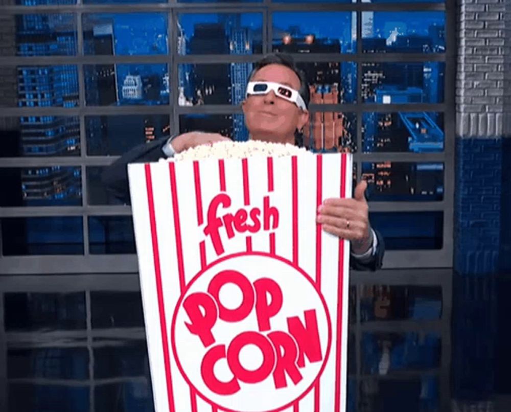 a man wearing 3d glasses holds a giant bucket of fresh popcorn