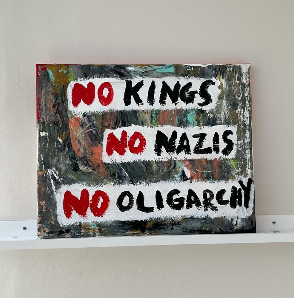 An acrylic painting, 16” by 20”, with three white horizontal slashes over a chaotic abstract background. On the white slashes is written in paint:
NO KINGS
NO NAZIS
NO OLIGARCHY.

The “No”s are painted in red and the other words are painted in black. (With “oligarchy” nearly running off the canvas and the last three letters of the word being scrunched together.)