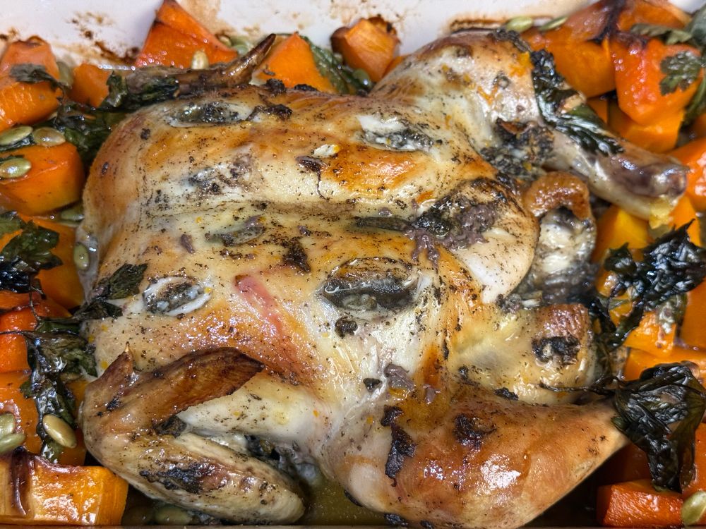 Roasted whole chicken with crispy golden-brown skin, seasoned with herbs and spices.