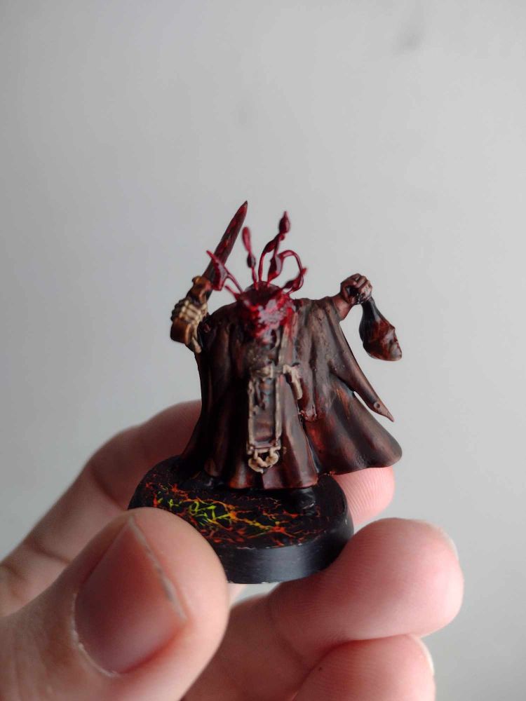 A miniature of a Trench Crusade guy with a severed head and goo shooting our of the neck