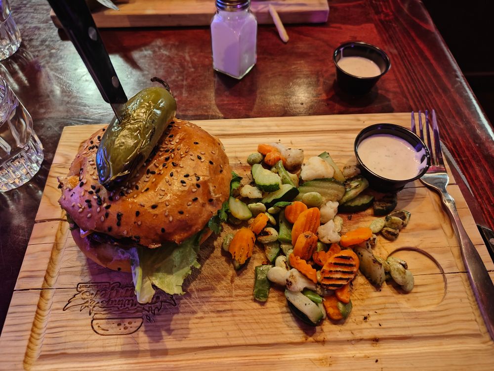Burger and veggies, on a cutting board.