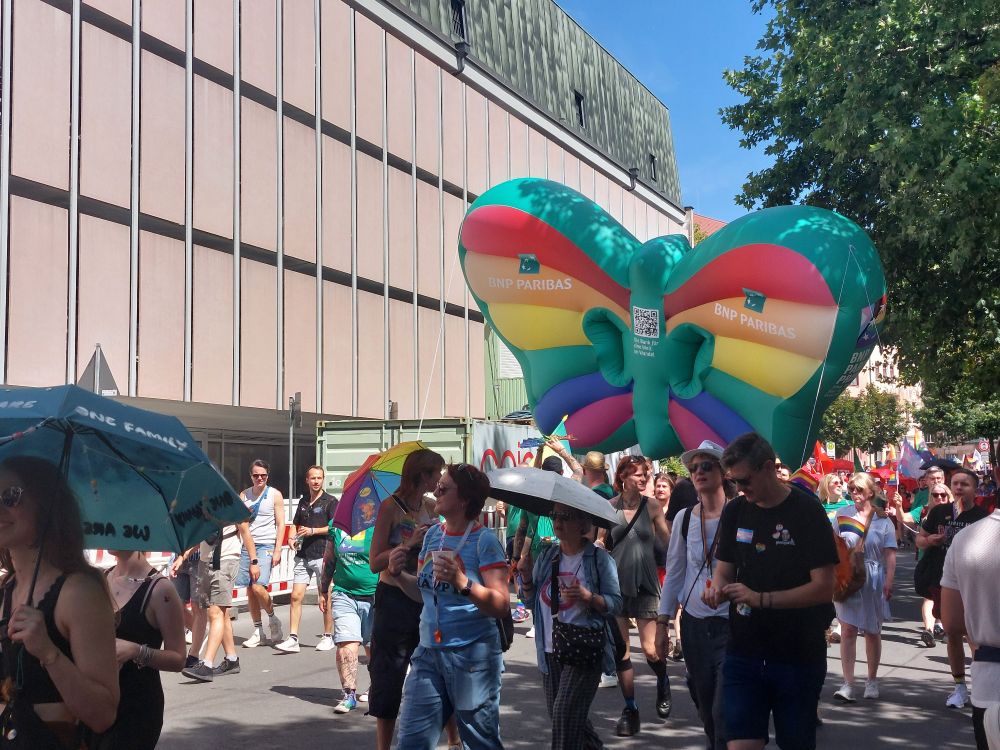 Menschen beim CSD Umzug mit einem großen bunten aufgeblasenen Schmetterling