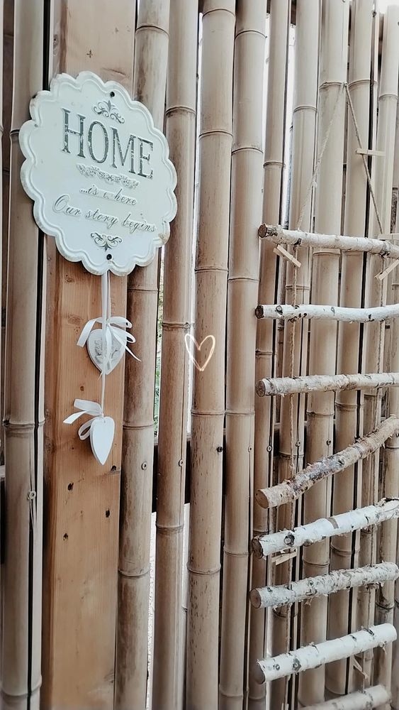 Parete di canne con scaletta a pioli decorativa e ciondolo decorativo con scritta "Home is where our story begins". 
