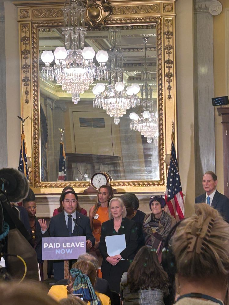 Photo of Senator Andy Kim at a podium that says “paid leave now” next to Senator Gillibrand, Rep DeLauro, and Senator Wyden
