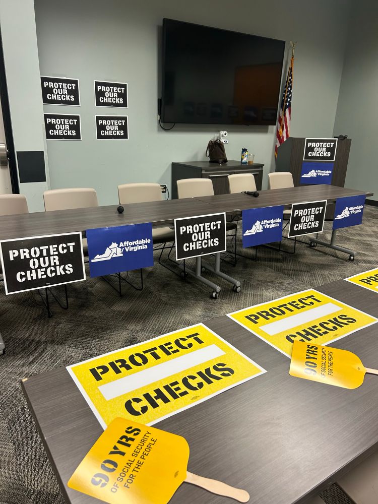 Picture of a meeting room decorated with signs that say “protect our checks” and “affordable Virginia”