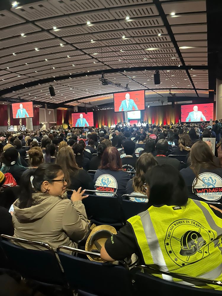 Conference hall full of women in union gear and screens showing NABTU president Sean McGarvey addressing the group 