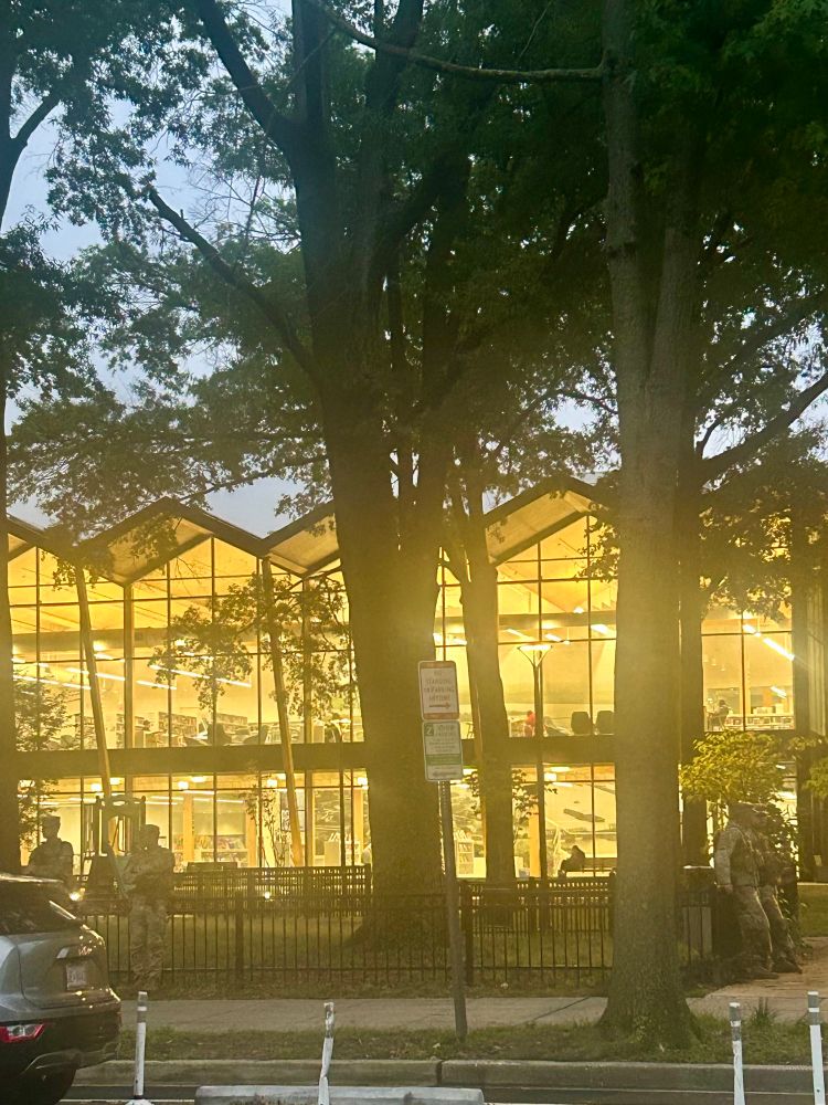 Picture of 4 of 8 National Guard members surrounding a brightly lit public library 