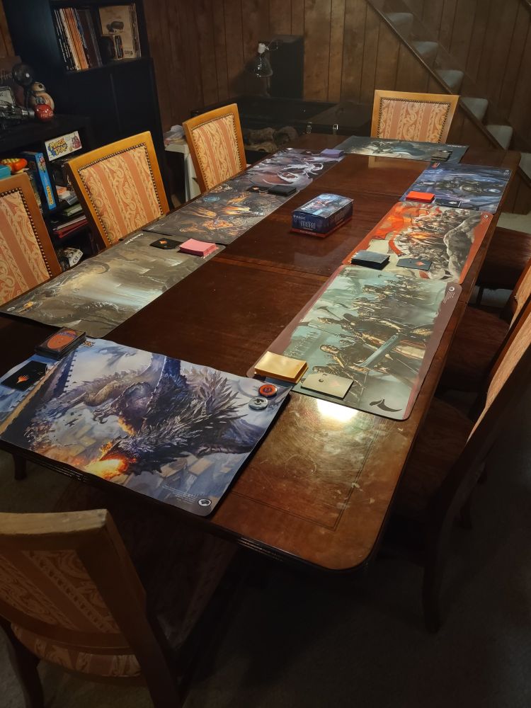 A basement table set up with 8 playmats, 8 sets of 40 sleeves, 8 life dials, and enough packs of innistrad remastered mtg set to run the draft. 