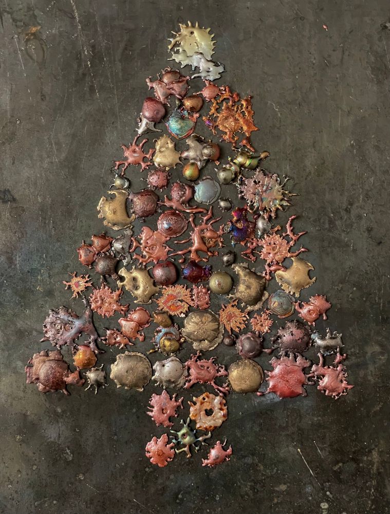 Splatters of molten copper arranged into the shape of a Christmas tree. When molten copper drops onto a hard surface they form shapes resembling different cell types. 