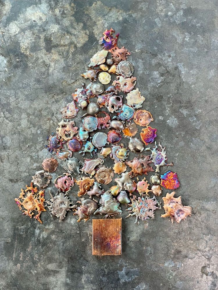 Colorful drops of molten copper shaped into a Christmas tree.