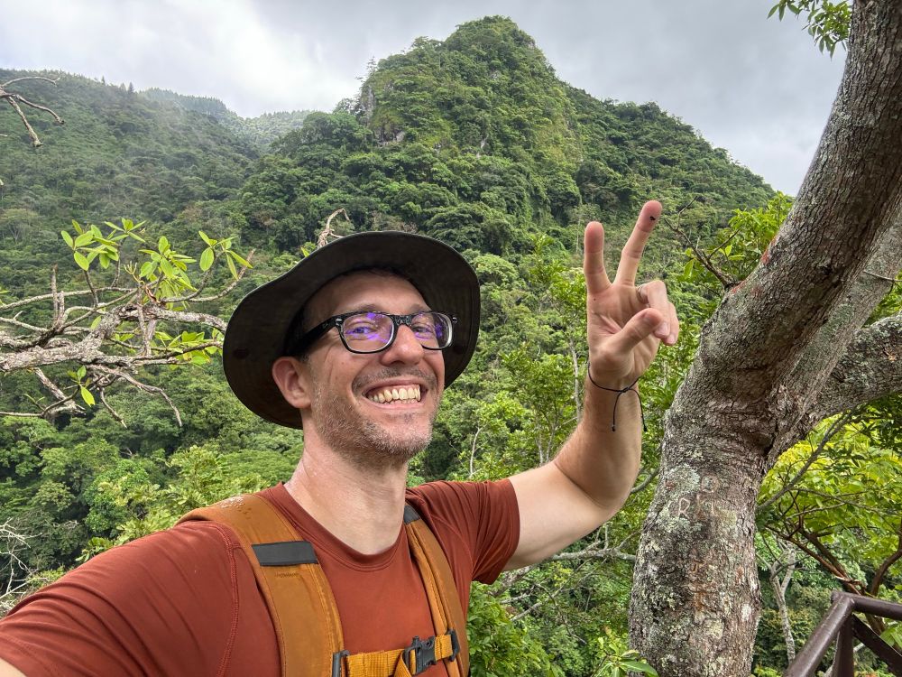 I’m smiling giving a peace sign from the top of an observation deck overlooking the Panamanian rainforest.