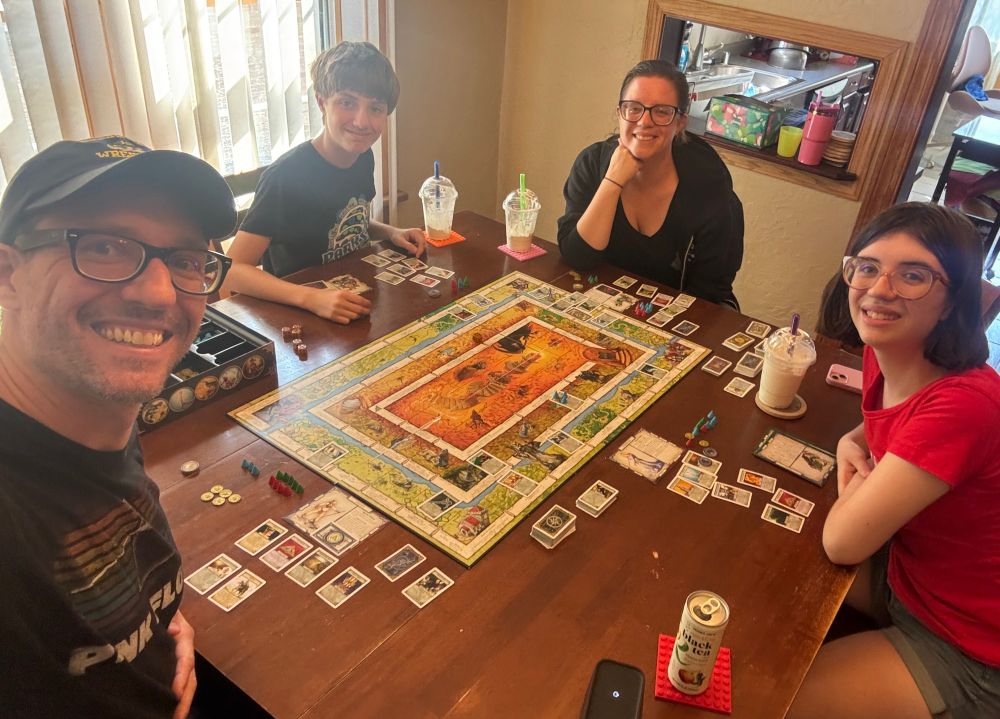 Me and my family of 4 smiling, sitting around a big game of Talisman in our dining room. 