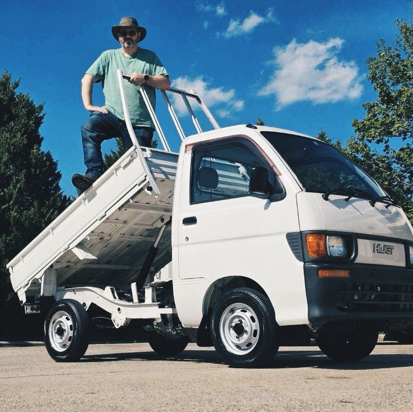 Magnus standing in the tilt bed of his Kei truck 