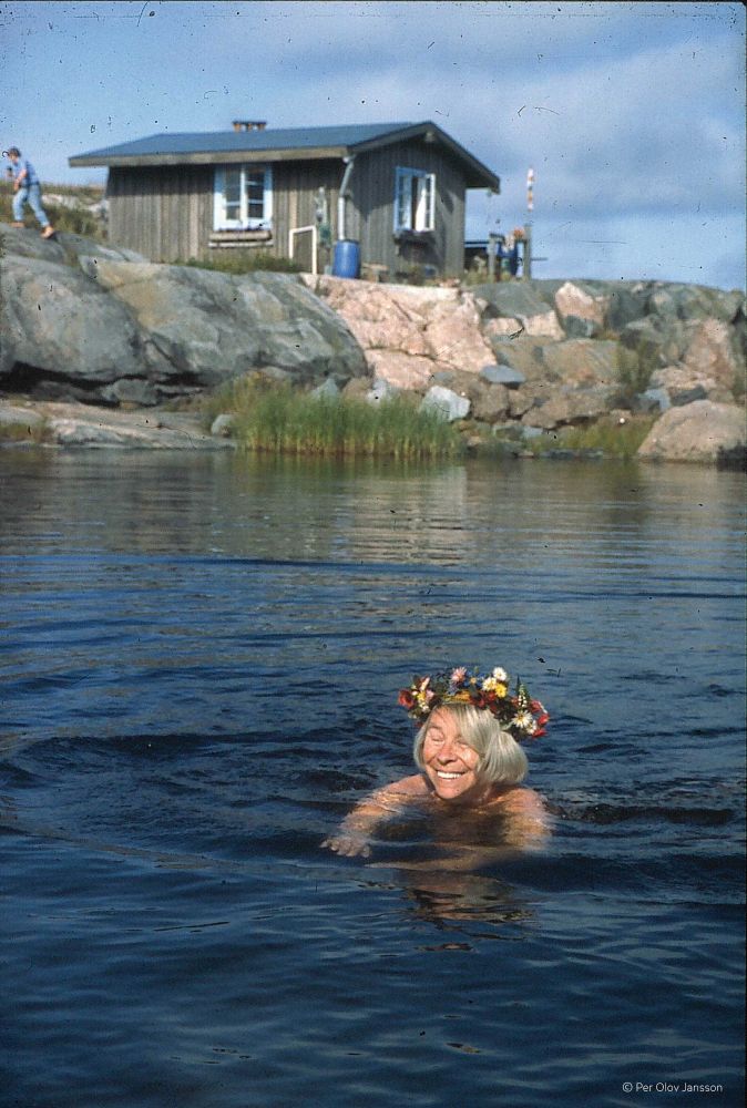 Tove Jansson swimming with her birthday flower crown on Klovharun.