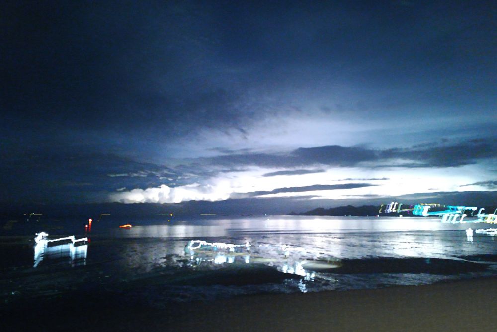 une plage la nuit avec un orage au loin. Pose longue.