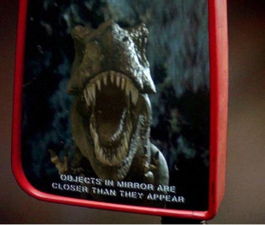 Mr Tyrannosaurus the Rex chasing a car, as seen through wing mirror