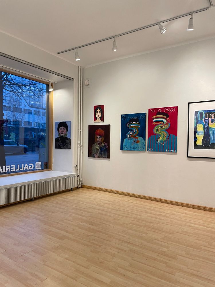 A photo from an art gallery. Window to the street, colorful portrait paintings on the wall. 